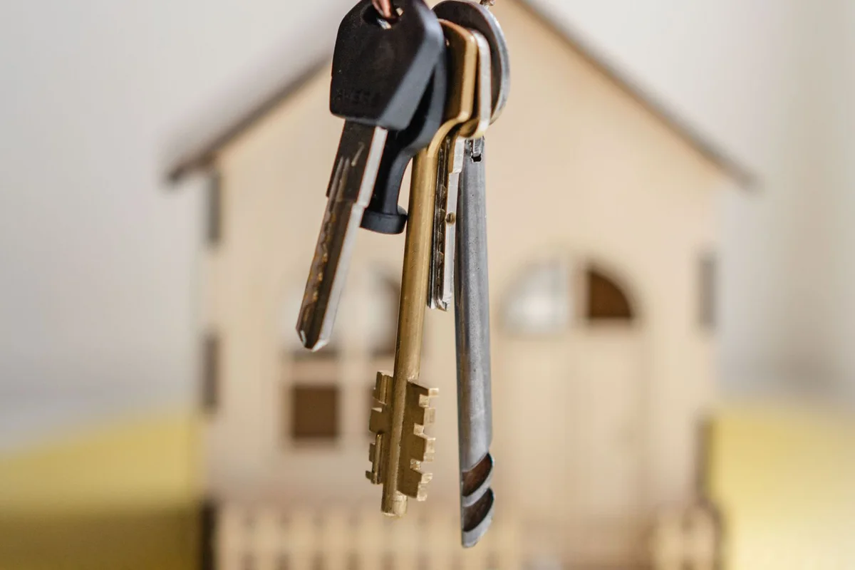 A real estate professional holding house keys beside a model home