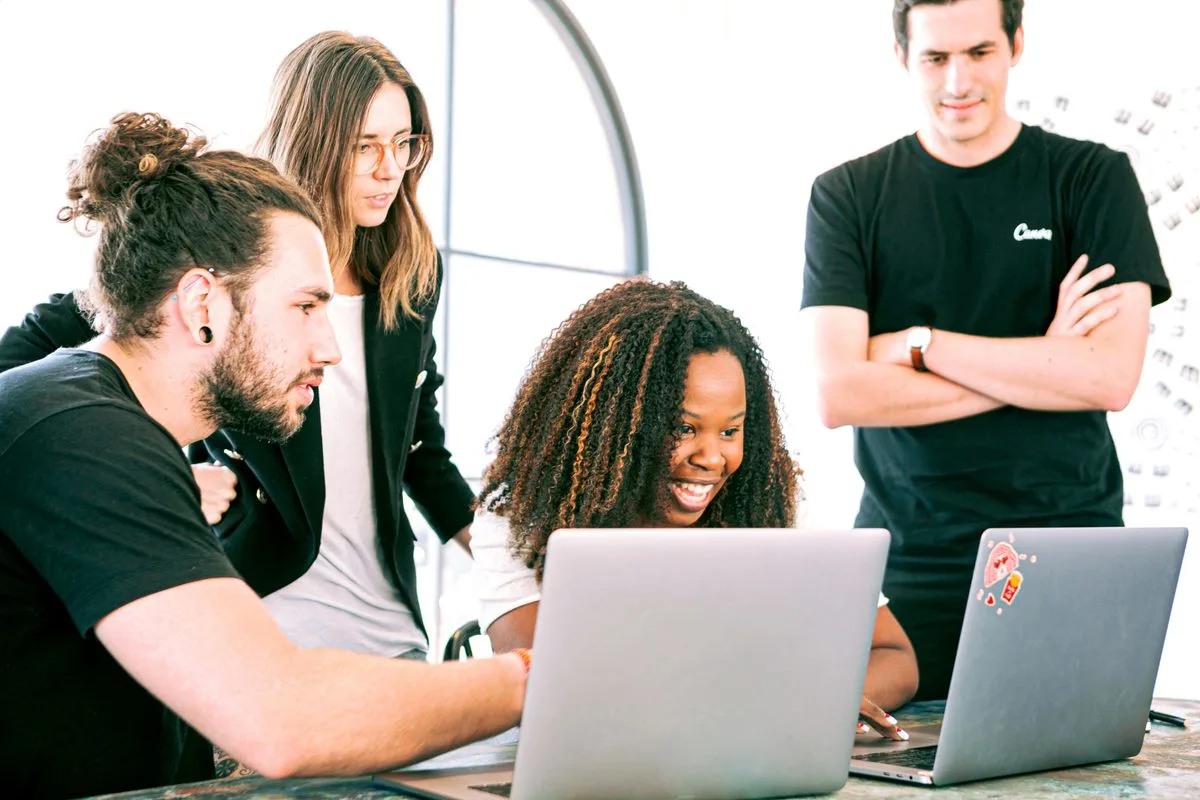 Developers collaborating at laptops in a bright workspace